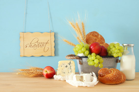image of fruits, bread and cheese in the tin basket over wooden table.