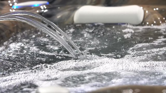 4K footage of jacuzzi jet of blue water with bubbles, stream liquid background