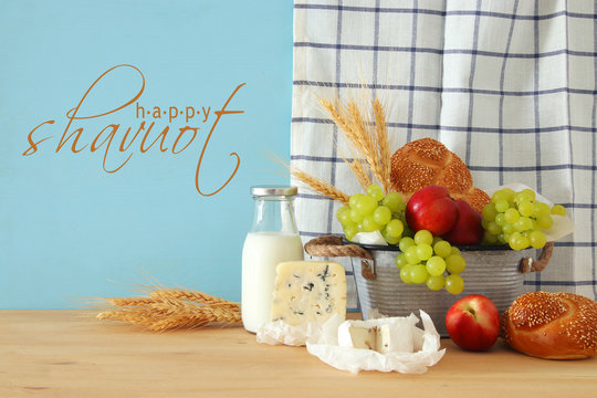 image of fruits, bread and cheese in the tin basket over wooden table.