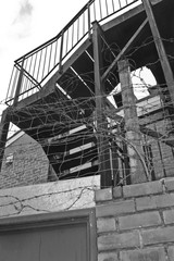 Industrial staircase surrounded by barbed wire.
