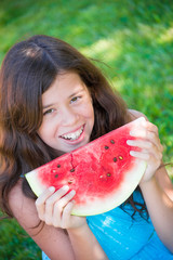 Girl eating juicy watermelon outdoors on grass