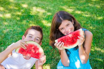 Two children eating juicy watermelon outdoors on grass