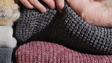Woman puts the knitted warm clothes in a pile - Powered by Adobe