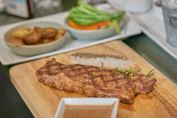 Steak with dip ,pepper,salt and thyme leaf on wooden plate