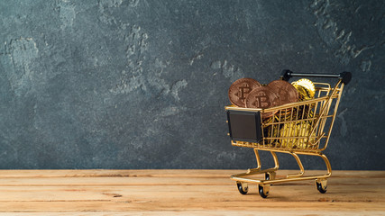 Bitcoin coin in shopping cart on wooden table
