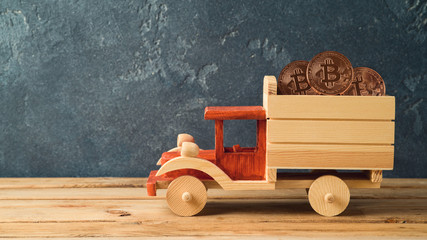 Bitcoin coin in toy truck on wooden table