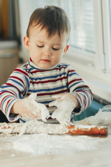 Fototapeta premium the child makes dough from flour house kitchen, played with the little chef
