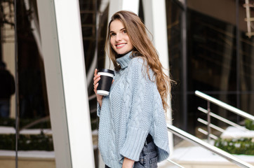 Fototapeta na wymiar Young attractive lady with long curly hair with coffee to go, wearing stylish clothes 