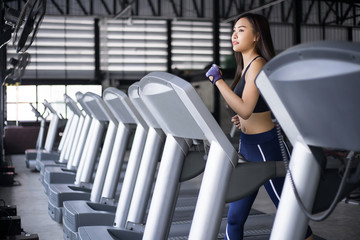 Young beautiful lady fitness training on running machine and smiling in gym