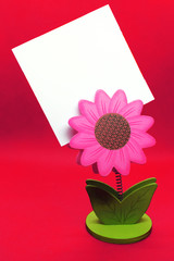 Pink flower shape paper holder with blank sticker with copy space for text, message or drawing on red background as colorful template for mothers, fathers, valentines, wedding or birthday greeting car