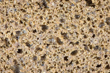 The rye brown or black bread background or texture. The macro shot is made by means of stacking technology