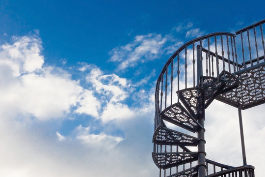 Spiral staircase against the blue sky with clouds