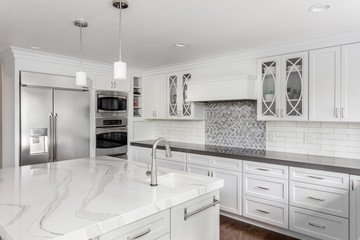Kitchen in New Luxury Home with White Cabinets, Stainless Steel Appliances, and Large Island with Sink