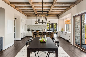 Stunning dining room and kitchen in new luxury home.Wood beams and elegant pendant lights accent...