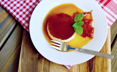 Caramel custard desert on white dish with wooden background