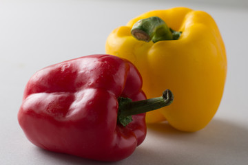 Yellow and red organic bell pepper on gray background with shadow