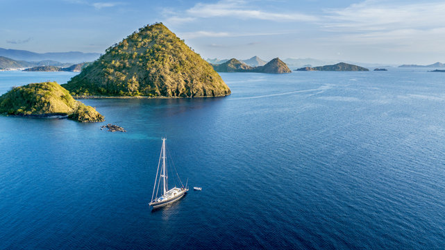 Sailboat with island under blue sky
