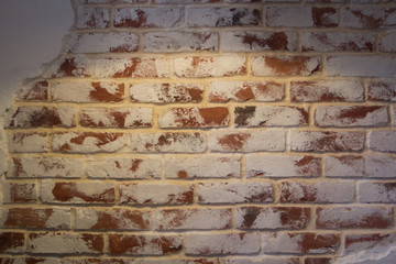 old red brick wall with white peeling paint under the light of a lamp