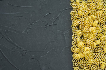 Macaroni ruote Beautiful decomposed pasta with the right, on its side on a black textured background. Close-up view from the top. Free space for text.
