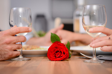romantic dinner love couple hands closeup together with a red rose on valentine restaurant