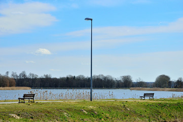 Fototapeta na wymiar Lampa uliczna i dwie ławki nad jeziorem.