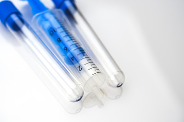 Syringes and test tubes lying on a white table. Medical background concept.