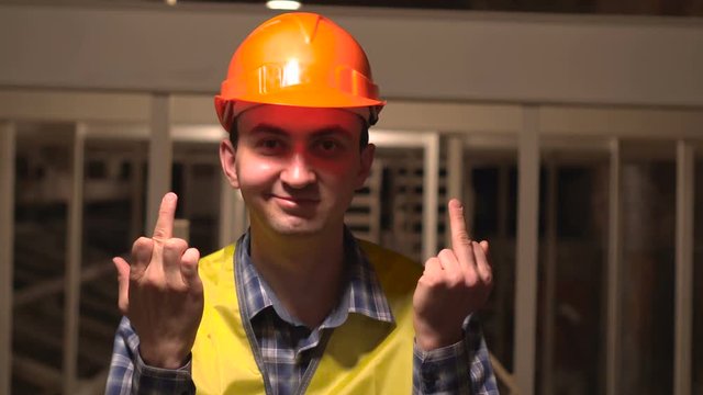 On a construction site, a worker or an engineer or architect is making obscene hand gesture by showing middle finger.