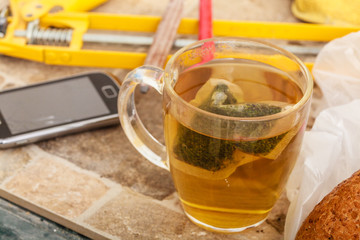 Cup of tea and smartphone in messy interior