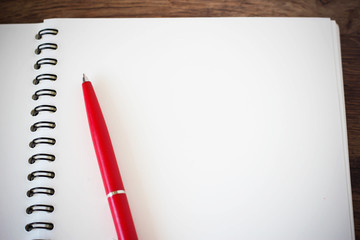 Notebook and red pen on a wooden surface