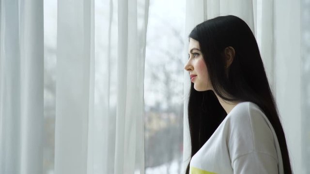 beautiful young caucasian woman looking out the window. waiting expectation anticipation concept
