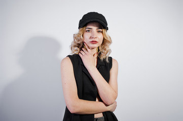 Studio portrait of blonde girl in black wear and cap against white background.