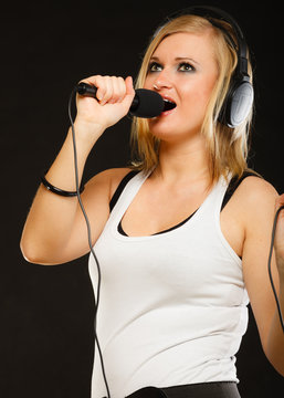Woman singing to microphone wearing headphones