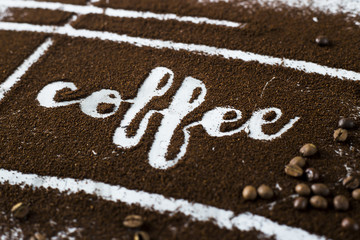 The word coffee is written on ground coffee next to coffee beans. Coffee Industry