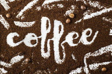 The word coffee is written on ground coffee next to coffee beans. Coffee Industry