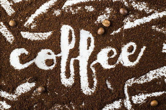 Fototapeta The word coffee is written on ground coffee next to coffee beans. Coffee Industry