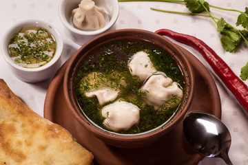 Georgian khinkali, soup with greens in a ceramic bowl
