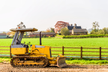 A small yellow construction bulldozer over British countryside