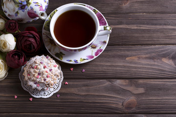 Teapot tea cup and cake on brown wooden table.