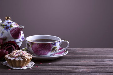 Teapot tea cup and cake on brown wooden table.