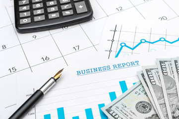 Business concept. Calculator, pen and money on the financial graphs.