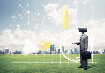 Camera headed man standing on green grass against modern citysca