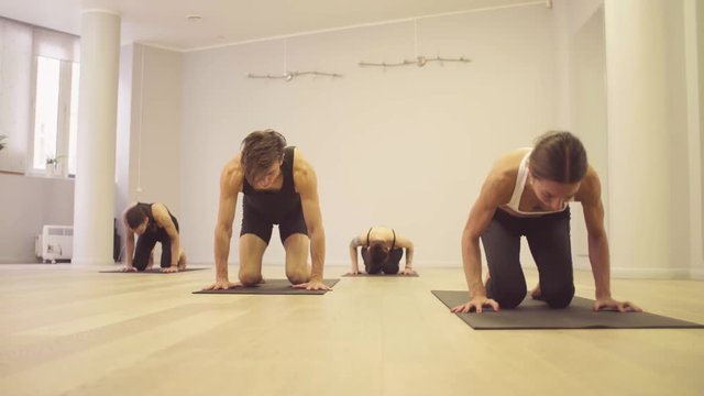 Yoga class. People doing yoga asanas in bright studio. Ashtanga yoga. Headstand - shirshasana