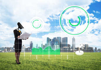 Camera headed woman standing on green grass against modern cityscape