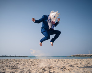 Stylish man in funny mask and suit jumps on beach © Sergey_T
