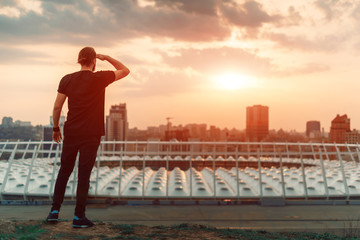 Fototapeta na wymiar backwards guy looking at sunrise skyline over a seaside city