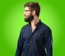 Young hipster man with big beard side view portrait over green background