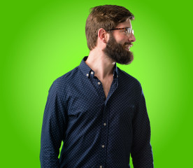 Young hipster man with big beard side view portrait over green background