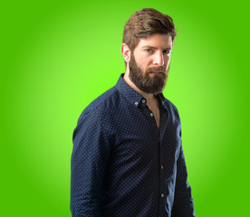 Obraz premium Young hipster man with big beard doubt expression, confuse and wonder concept, uncertain future over green background