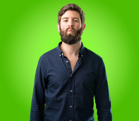 Obraz premium Young hipster man with big beard expressing love, blows kiss at camera, flirting over green background