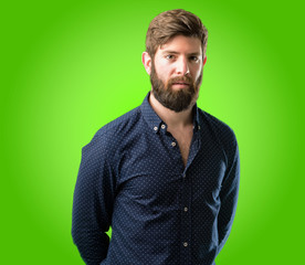 Young hipster man with big beard confident and happy with a big natural smile looking at camera over green background